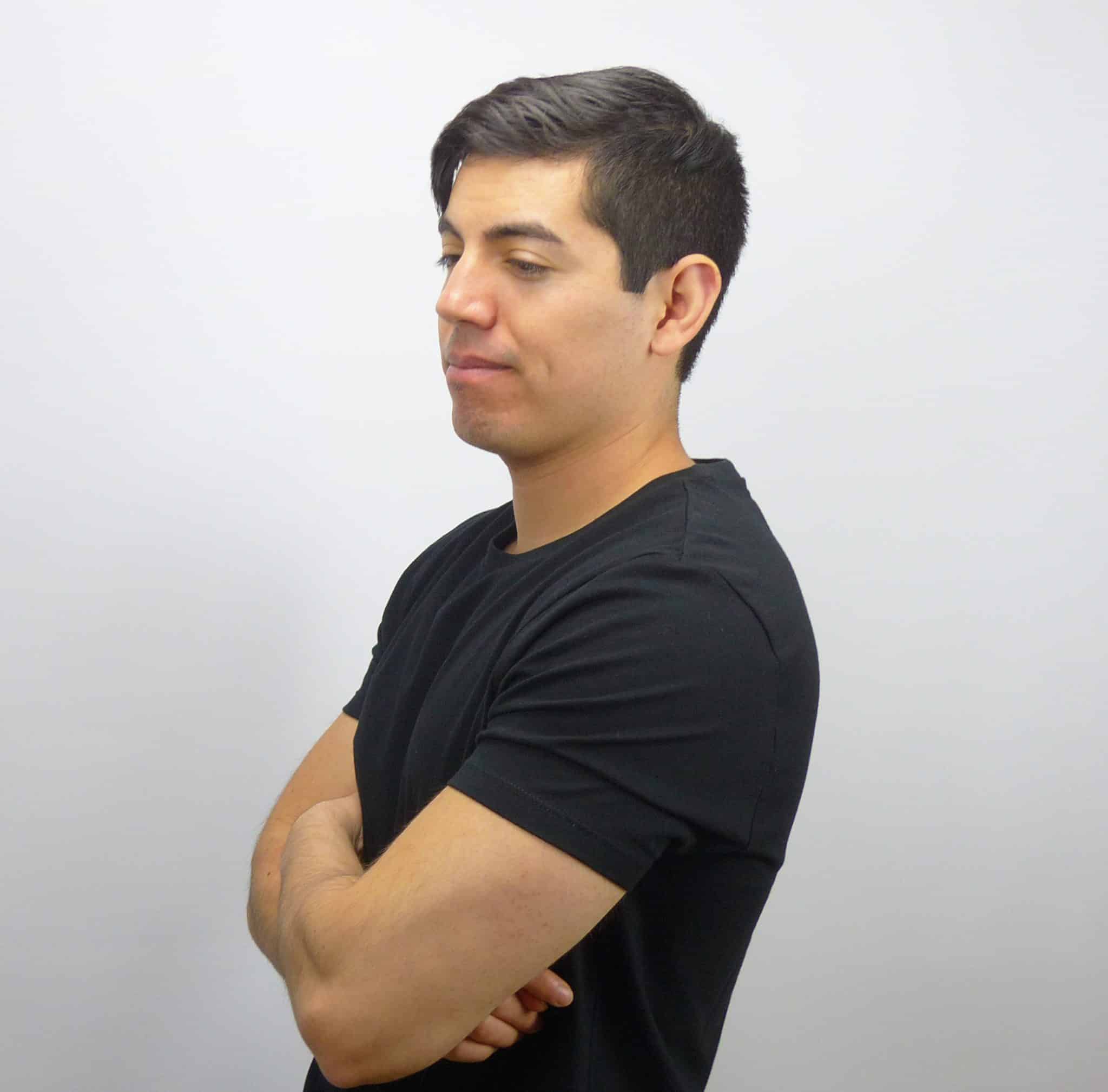 A man with his arms crossed in front of a white background.