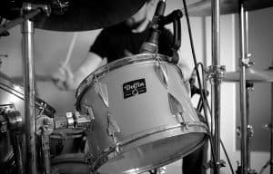 A man passionately playing the drum kit in a recording studio.