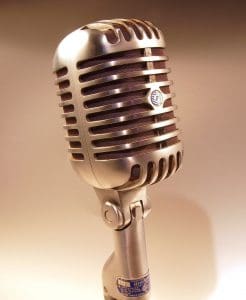 A silver microphone, representing female vocal pronunciation, is shown against a white background.