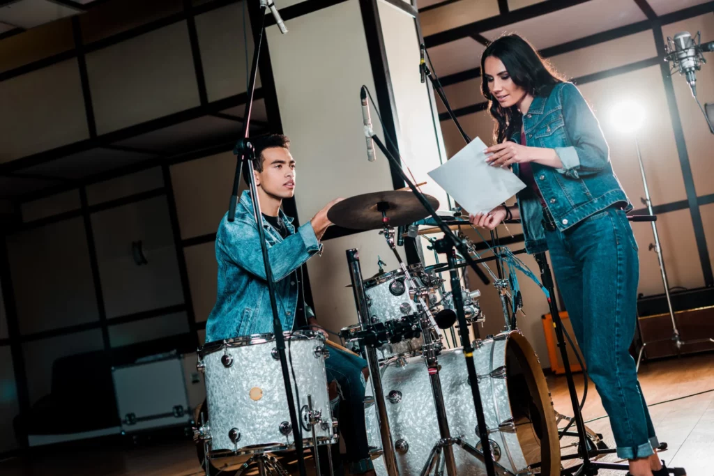 pretty singer and handsome mixed race drummer talking in recording studio